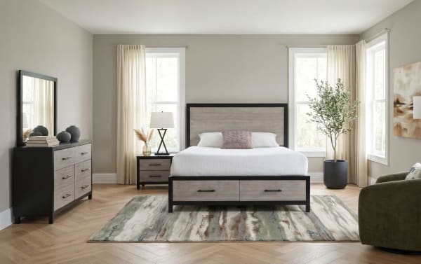 Modern bedroom with a queen-size bed featuring a black metal frame and light wood panels, matching nightstand and dresser, neutral decor, and large windows.
